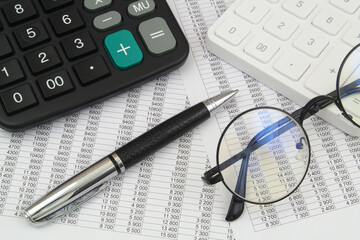 White and black calculators, glasses and pen on financial bills. Accountancy and arbitrage concept.