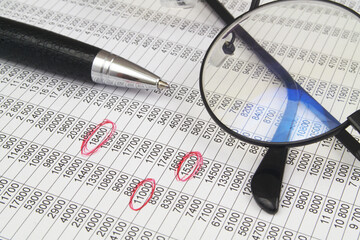 Close-up of documents with red marks, pen and eyeglasses.	