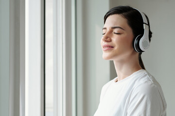 Young woman enjoying sunlight and listening to affirmations in the morning