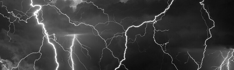 Fork lightning striking down during summer storm in black and white