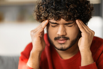 Closeup Shot Of Stressed Young Indian Guy Suffering From Headache At Home