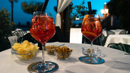Two glasses of campari spritz served on a table. Moment of aperitif in the open square. Summer,...