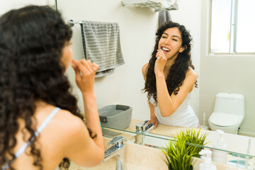 Attractive woman flossing and brushing her teeth