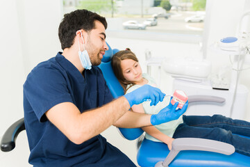 Obraz premium Pediatric dentist showing the correct way to brush teeth to a little child