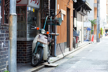 赤いのれんと出前のバイクがあるラーメン屋の外観