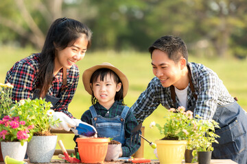 Family child girl helping parent care plant flower in garden. Young people mother, father and daughter gardening outdoor sunny nature background. Happy and enjoy in spring and summer day