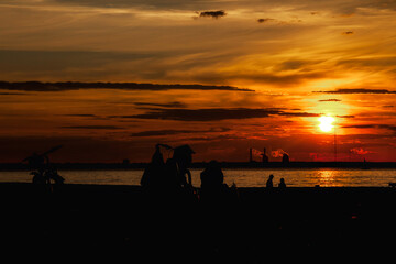 Panorama of silhouettes people and bike at urban seaside at amazing city sunset background. Panoramic view of evening urban landscape for ad poster. Vitality and city life concept. Copy text space