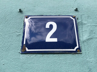 Metal sign with the number two on a green wall