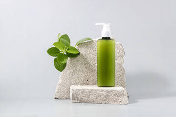 container for cosmetics on the podium made of stone and a sprig of mint on a gray background