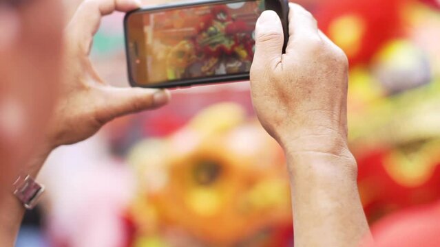 Man's hand using a smartphone to record a lion dance during Chinese New Year.
