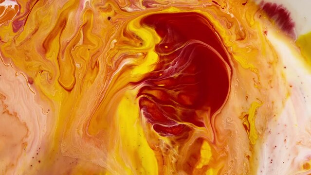 Yellow and orange liquid paint swirling in an abstract pattern. Background. 