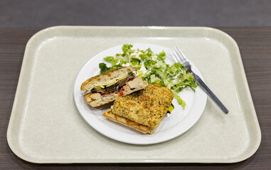 Tofu sandwich avec légumes grillés et salade verte sur plateau gris pâle