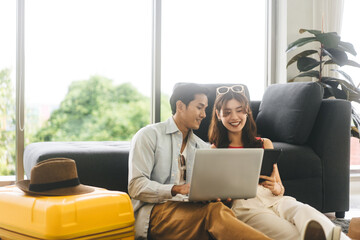 Young adult southeast asian couple using laptop for getting ready for holidays travel trip in...