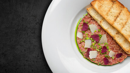 Meat tartar, with green onions, and bread toast, on a plate