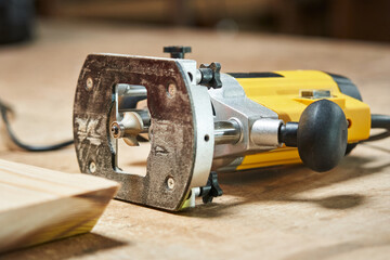 side view of the base and cutter of a hand router for woodworking. he lies on a wooden table