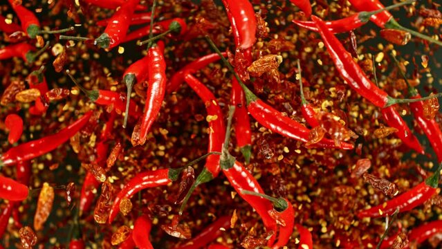Super slow motion of flying and rotating red chilli peppers. Filmed on high speed cinema camera, 1000 fps, placed on high speed cine bot, following the target. Black background.