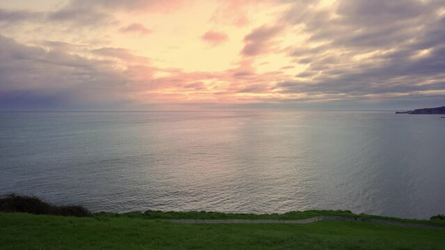 Drone view of a golden sunset over the sea horizon on a calm and serene day, Gijon, Asturias