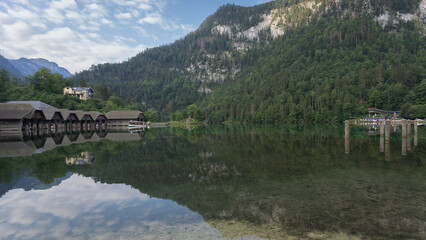 Bank of still alpine lake with huts and boathouses, Konigssee, Germany
