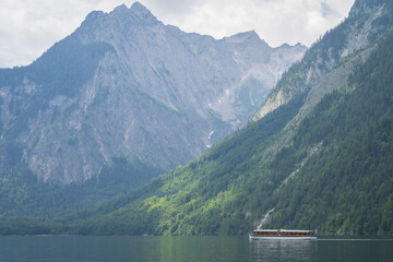 Small boat sailing on alpine lake surrounded by high mountains , Konigssee, Germany