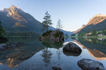 Fototapeta na wymiar Crystal clear alpine tarn with rocky islands with tree on them during sunrise, Hintersee, Germany