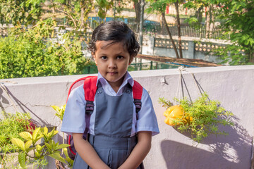 Cute little Indian girl wearing uniform having backpack and water bottle. 