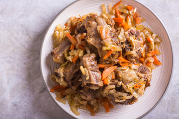 Fototapeta premium Close up of stewed oxtail with carrots and onions on a plate on the table top view