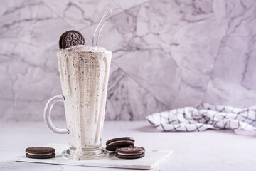 Milkshake of chocolate oreo cookies and ice cream in a glass with a straw