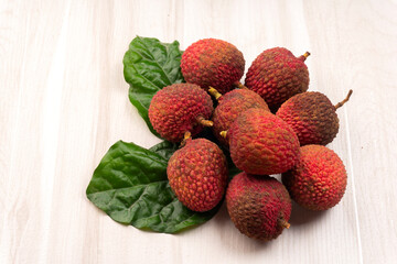 Fresh lychee with leaves isolated on wooden background.