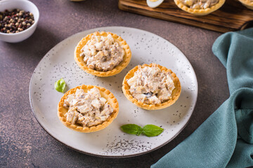 Tartlets filled with canned fish, eggs and mayonnaise on a plate