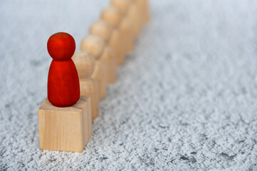 Red wooden figure on top of wooden block representing a leader leading other figure. Leadership...
