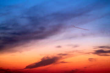 Sunset sky with red light of the setting sun. Evening clouds in the orange light of sunset rays
