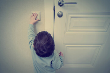 Little baby turns on the light by pressing the switch. Small child turns off the electric light at...