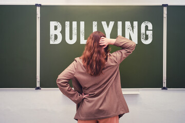 Text is a school bullying on the blackboard and a sad teacher in the classroom. Problems with...