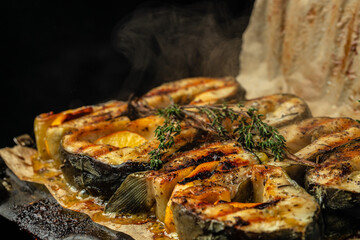 Grilled fish steak sturgeon with lemon herbs and spices, on a dark background, Restaurant menu,...