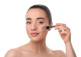 Woman applying foundation on face with brush against white background