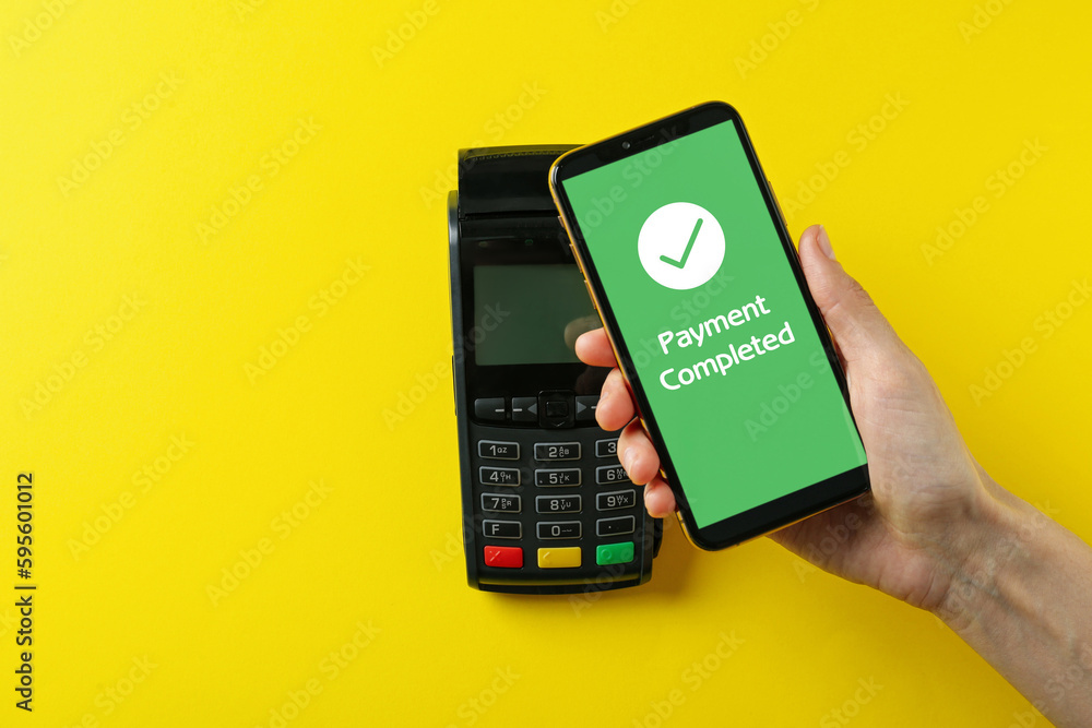 Wall mural woman using terminal for contactless payment with smartphone on yellow background, top view. transac