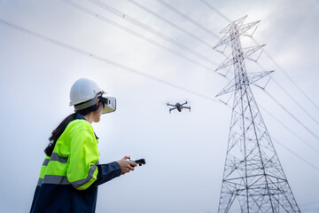 A female electrical engineer flying drone survey area of high voltage pylon with vr goggles at high...