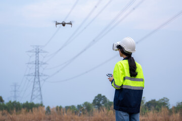 A female electrical engineer fielding wearing vr goggles using drone to inspect power station to...