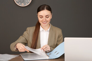 Businesswoman putting document into file folder at wooden table in office