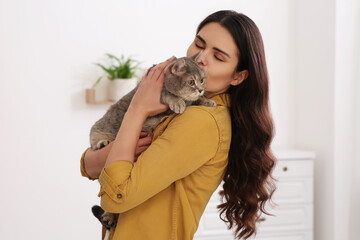 Young woman kissing her adorable cat at home