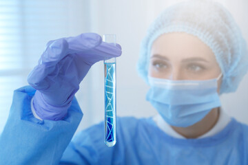 Genetics research. Scientist holding test tube with liquid and illustration of DNA structure in...
