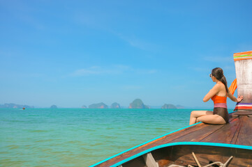 Fototapeta na wymiar A woman sitting on a boat looking at the beautiful sea view.Krabi,Thailand