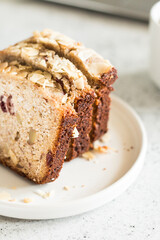 Banana muffin with nuts, almonds and berries on a white plate side view. Delicious fragrant pastries.