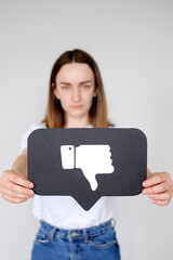 Sad young woman holding Dislike button icon of social media