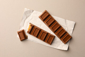 Tasty chocolate bars with paper wrap on light background, top view