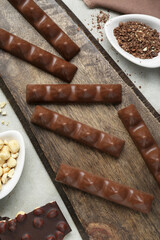 Tasty chocolate bars and nuts on light grey table, flat lay