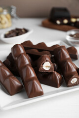 Tasty chocolate bars with nuts on white wooden table, closeup