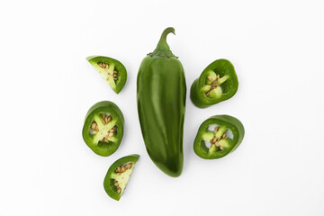Whole and cut green hot chili peppers on white background, flat lay