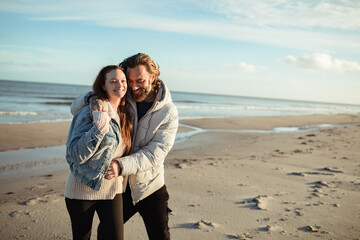 Young adult couple walking on a beach during cold weather