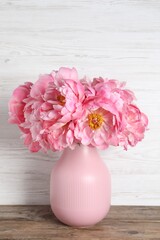 Beautiful bouquet of pink peonies in vase on wooden table